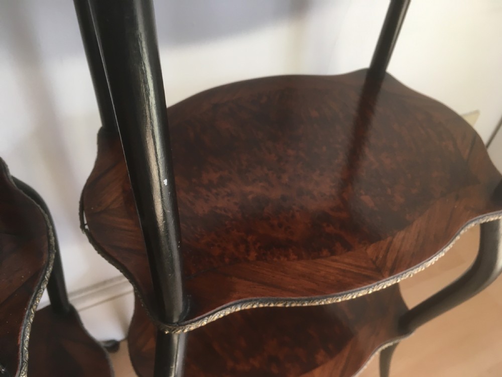 A pair of three-tiered French style side tables crafted from dark wood with inlaid marquetry work, gilt metal gallery rails, and cabriole legs. View XV