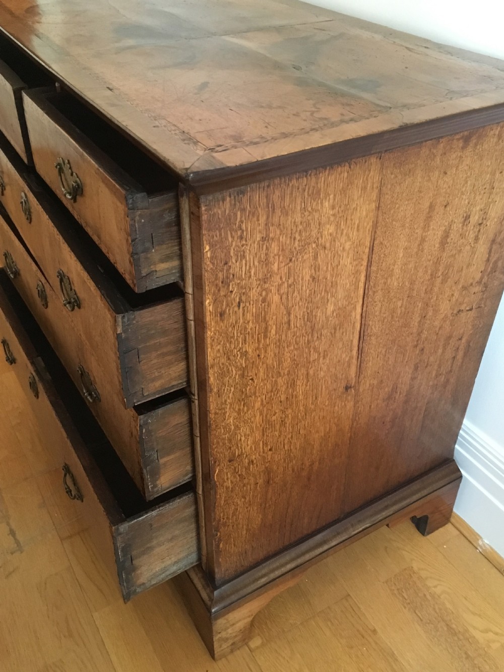 An eighteenth-century walnut chest of drawers featuring decorative poker work inlay, brass swing handles, keyhole escutcheons, and straight bracket feet. View III