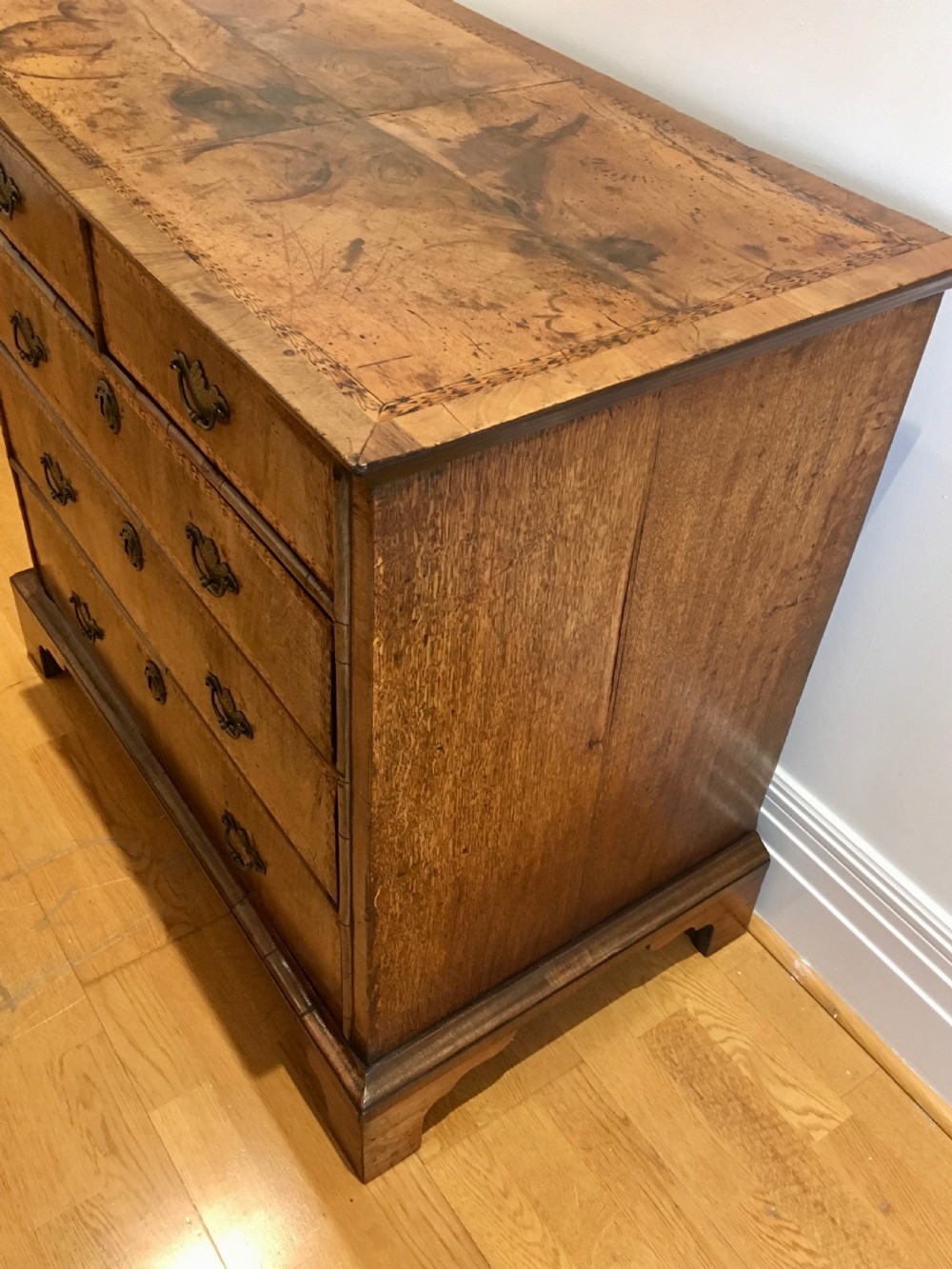 An eighteenth-century walnut chest of drawers featuring decorative poker work inlay, brass swing handles, keyhole escutcheons, and straight bracket feet. View VII
