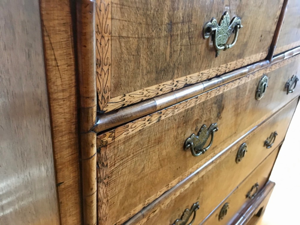 An eighteenth-century walnut chest of drawers featuring decorative poker work inlay, brass swing handles, keyhole escutcheons, and straight bracket feet. View XIII