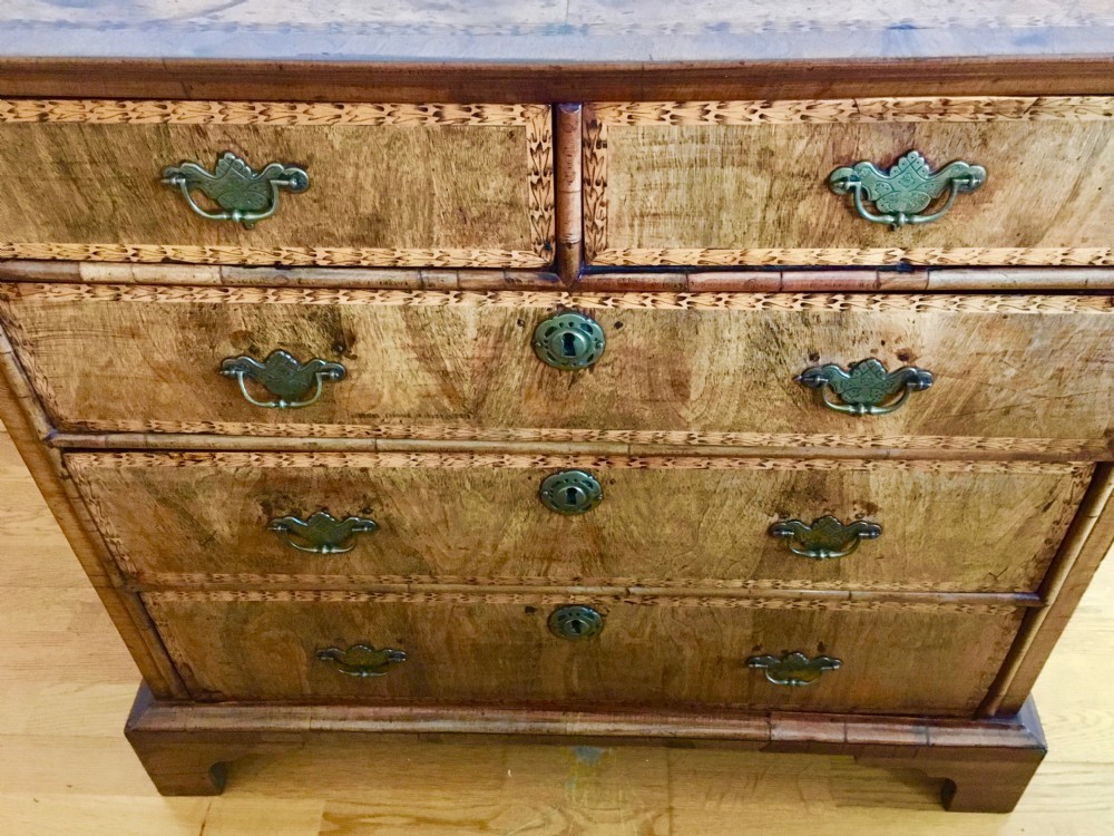 An eighteenth-century walnut chest of drawers featuring decorative poker work inlay, brass swing handles, keyhole escutcheons, and straight bracket feet. View XI