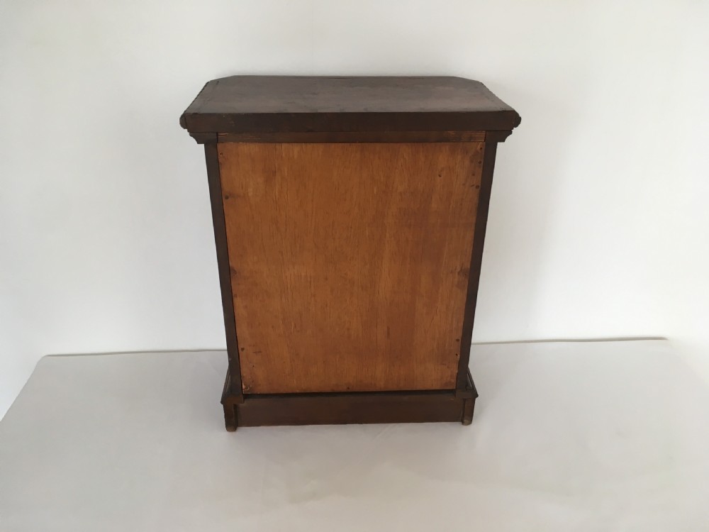 A small dark oak tabletop collectors cabinet featuring five inlaid drawers, turned wooden knobs, and a carved beaded top edge. View XIV