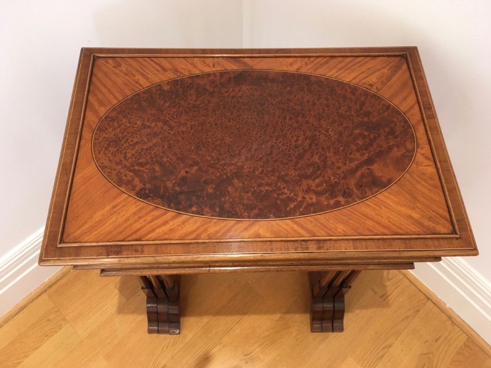 A set of three nested wooden side tables featuring rectangular tops with oval amboyna wood centres, inlaid satinwood borders, and slender turned legs. View III