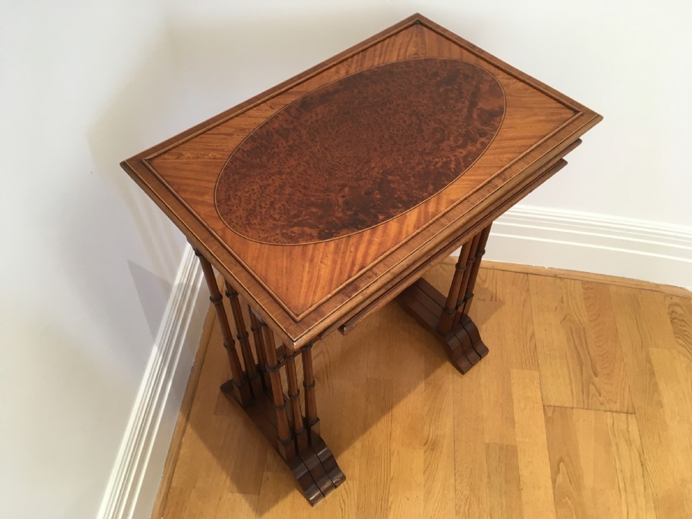 A set of three nested wooden side tables featuring rectangular tops with oval amboyna wood centres, inlaid satinwood borders, and slender turned legs. View IV