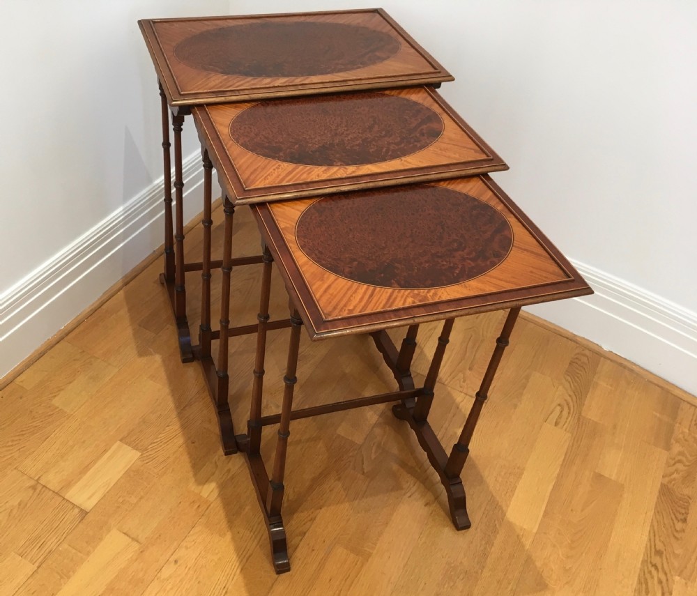 A set of three nested wooden side tables featuring rectangular tops with oval amboyna wood centres, inlaid satinwood borders, and slender turned legs. View V