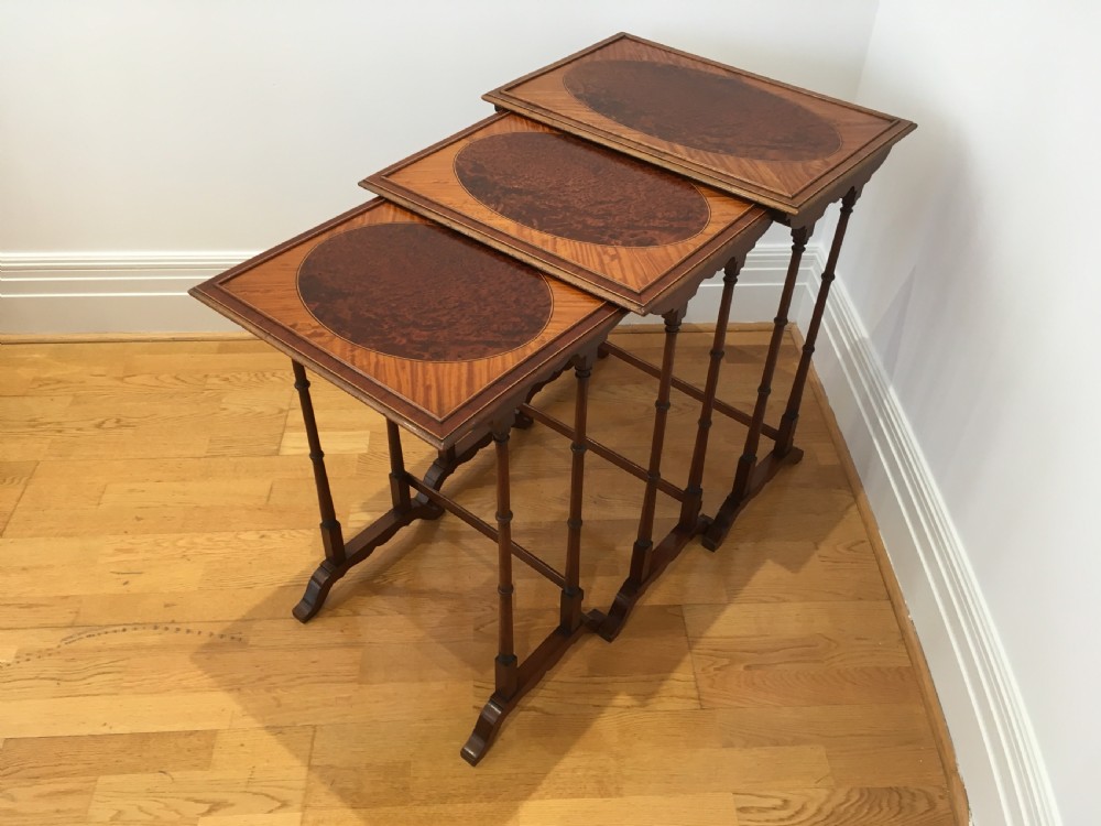 A set of three nested wooden side tables featuring rectangular tops with oval amboyna wood centres, inlaid satinwood borders, and slender turned legs. View VI