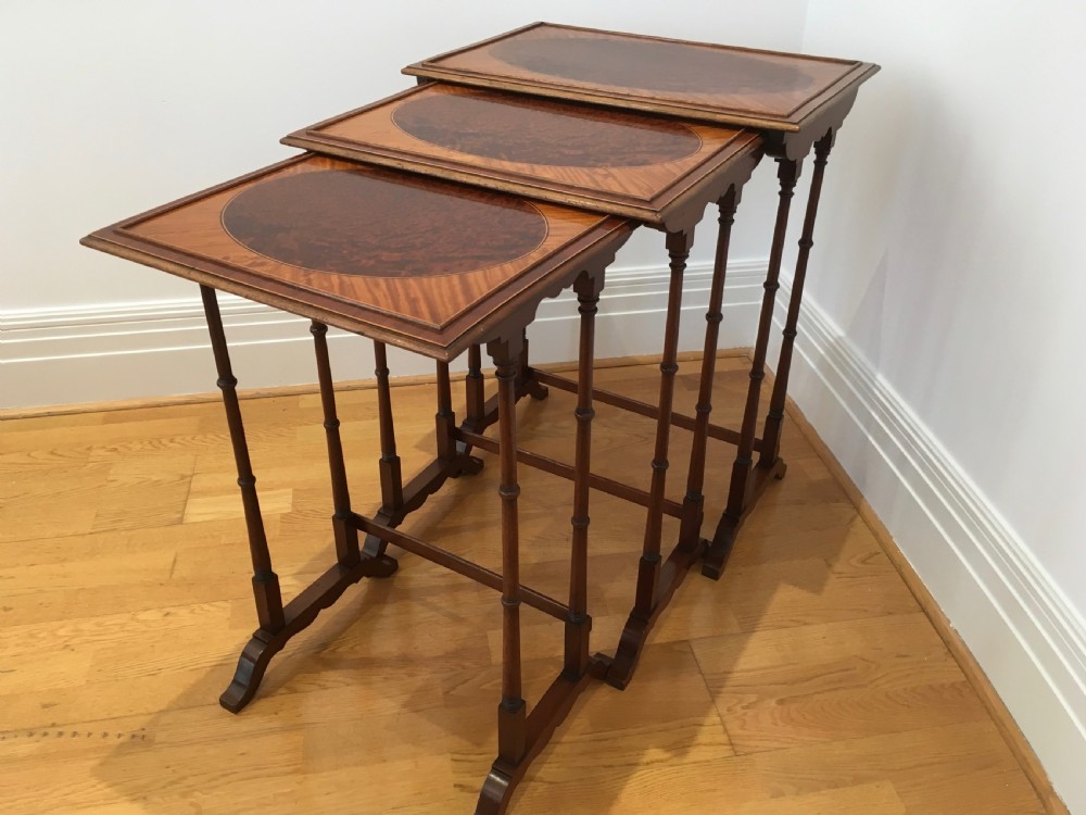 A set of three nested wooden side tables featuring rectangular tops with oval amboyna wood centres, inlaid satinwood borders, and slender turned legs. View VII