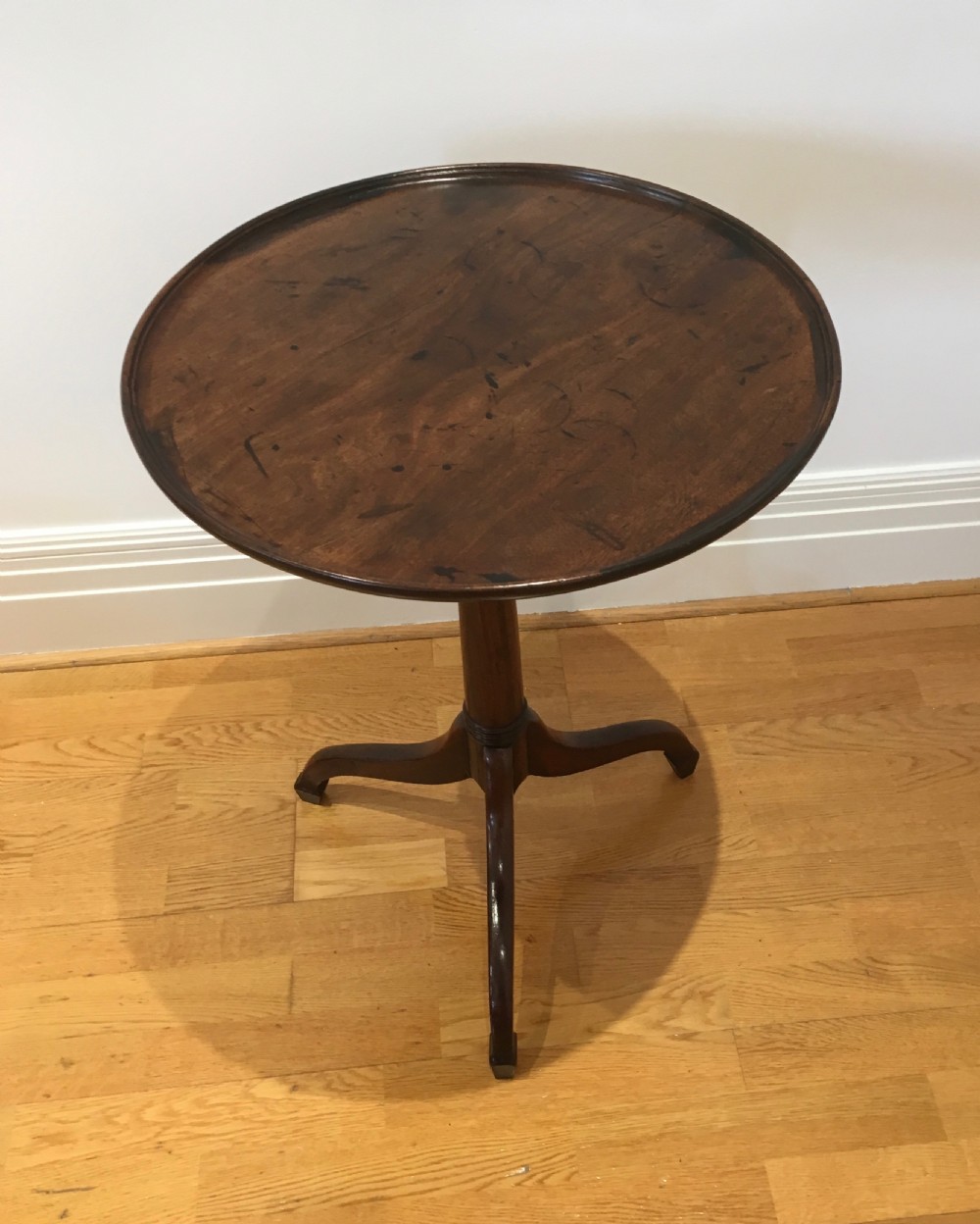 A Georgian dark mahogany tilt-top occasional table featuring a circular dished top supported by a turned central pedestal column and a tripod base with downswept legs. View III
