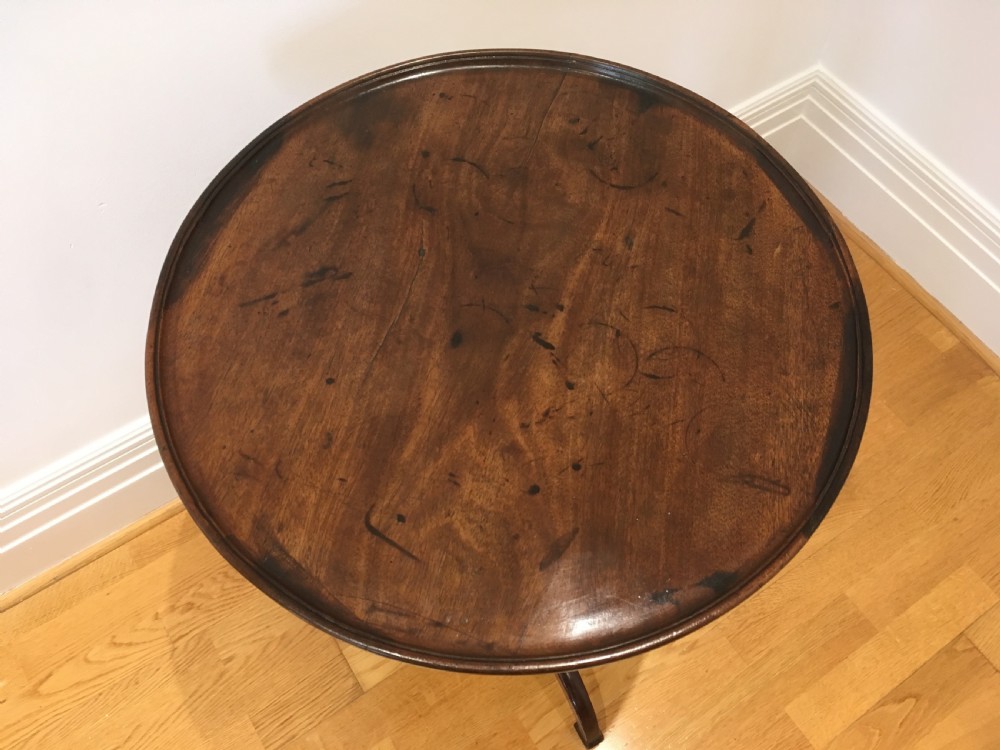 A Georgian dark mahogany tilt-top occasional table featuring a circular dished top supported by a turned central pedestal column and a tripod base with downswept legs. View VI
