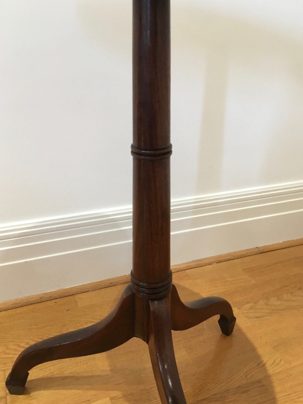 A Georgian dark mahogany tilt-top occasional table featuring a circular dished top supported by a turned central pedestal column and a tripod base with downswept legs. View VIII
