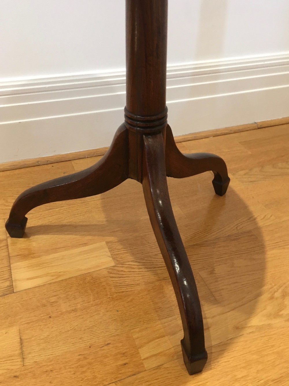 A Georgian dark mahogany tilt-top occasional table featuring a circular dished top supported by a turned central pedestal column and a tripod base with downswept legs. View IX