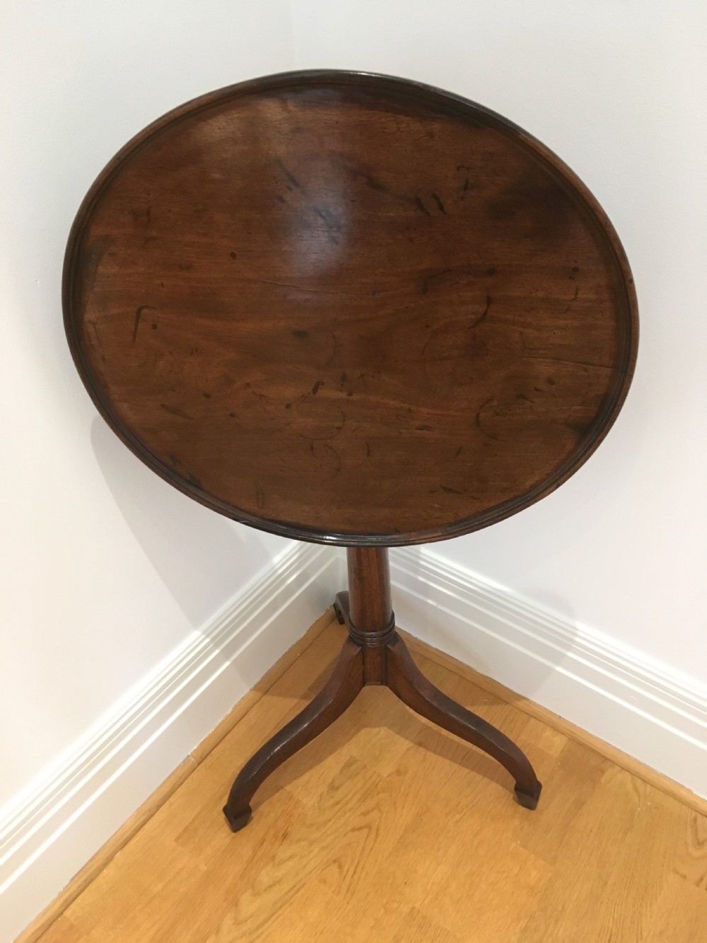 A Georgian dark mahogany tilt-top occasional table featuring a circular dished top supported by a turned central pedestal column and a tripod base with downswept legs. View XI