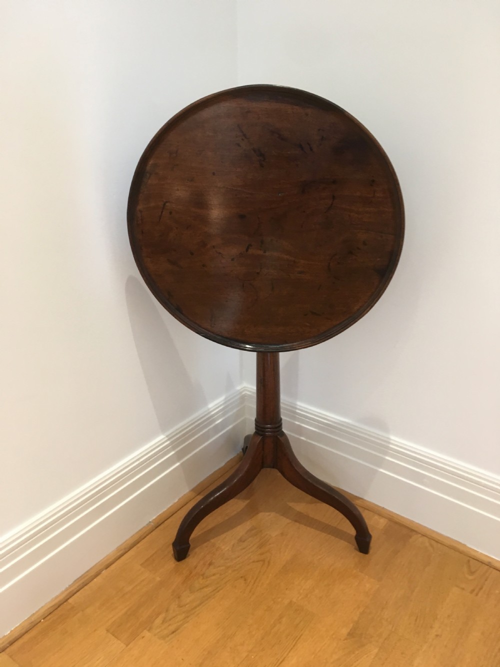 A Georgian dark mahogany tilt-top occasional table featuring a circular dished top supported by a turned central pedestal column and a tripod base with downswept legs. View XII