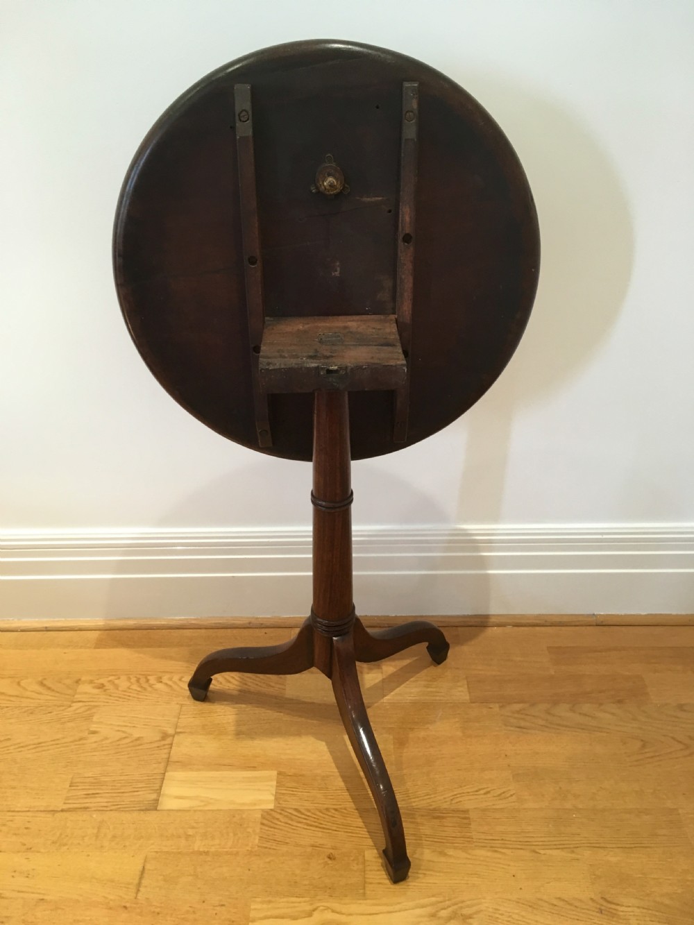 A Georgian dark mahogany tilt-top occasional table featuring a circular dished top supported by a turned central pedestal column and a tripod base with downswept legs. View XV