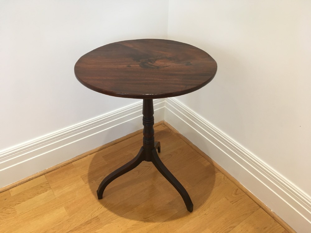A Georgian mahogany tilt-top table with a circular top locked in a vertical position on a turned central pedestal with three down-swept legs. View III