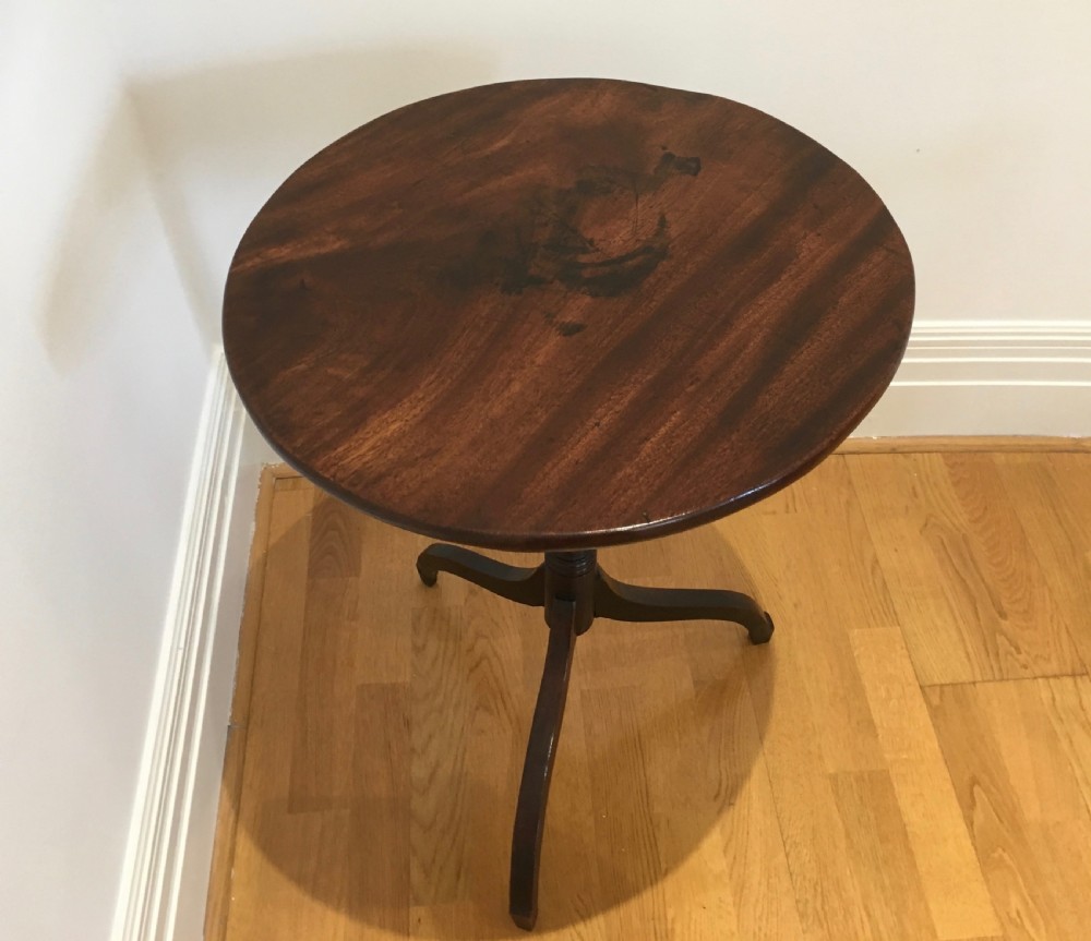 A Georgian mahogany tilt-top table with a circular top locked in a vertical position on a turned central pedestal with three down-swept legs. View VI