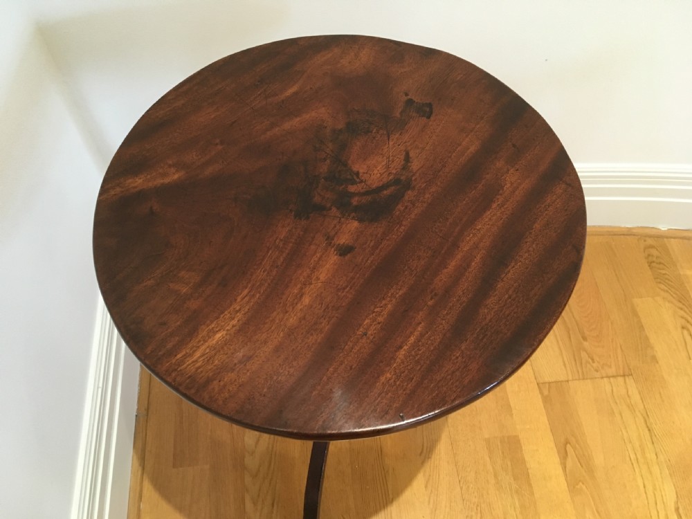 A Georgian mahogany tilt-top table with a circular top locked in a vertical position on a turned central pedestal with three down-swept legs. View VII