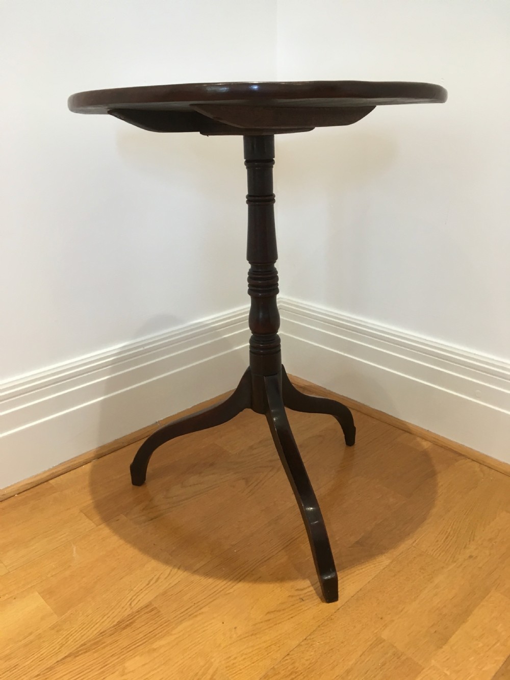 A Georgian mahogany tilt-top table with a circular top locked in a vertical position on a turned central pedestal with three down-swept legs. View VIII