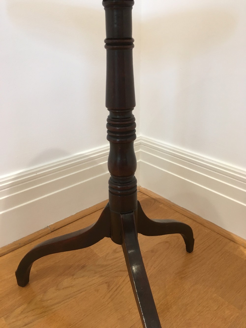 A Georgian mahogany tilt-top table with a circular top locked in a vertical position on a turned central pedestal with three down-swept legs. View IX
