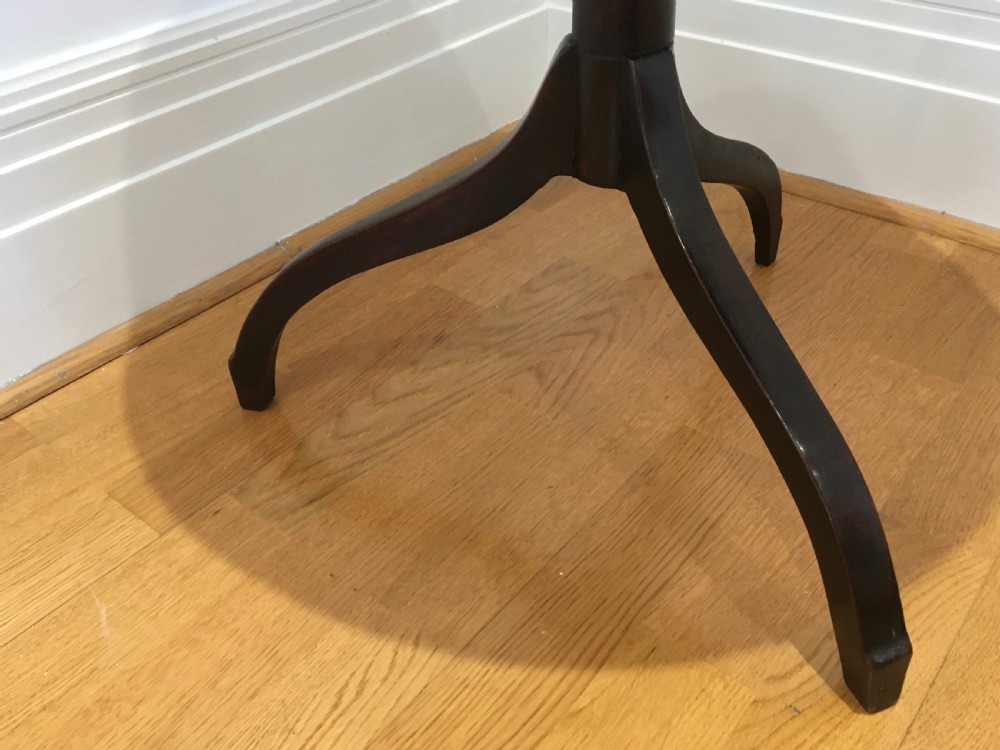 A Georgian mahogany tilt-top table with a circular top locked in a vertical position on a turned central pedestal with three down-swept legs. View X