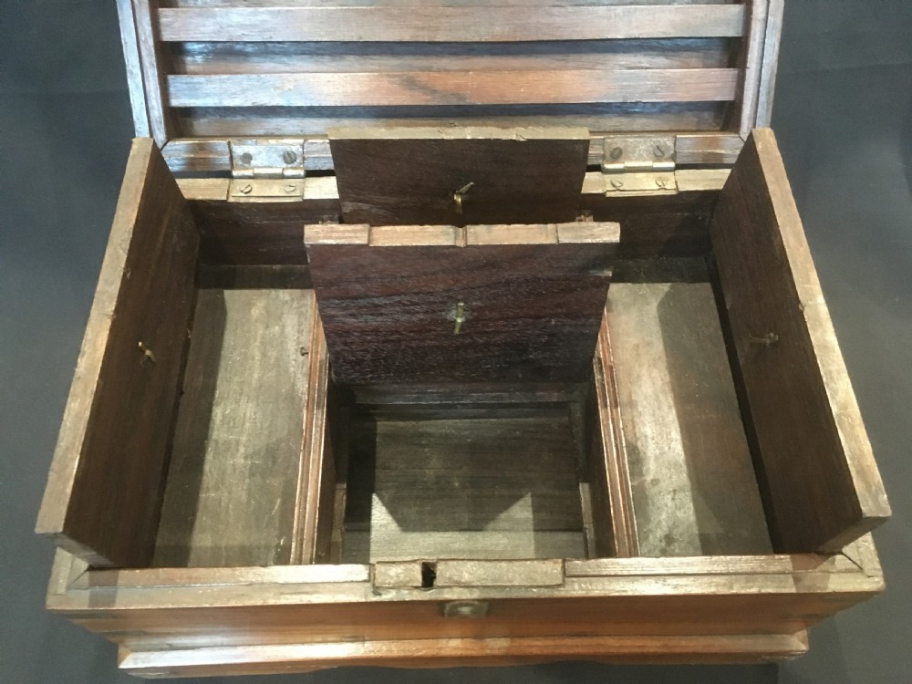 A rectangular warm brown oak desk box featuring brass bound corners, metal straps, a central brass oval cartouche, and a front keyhole escutcheon. View VI
