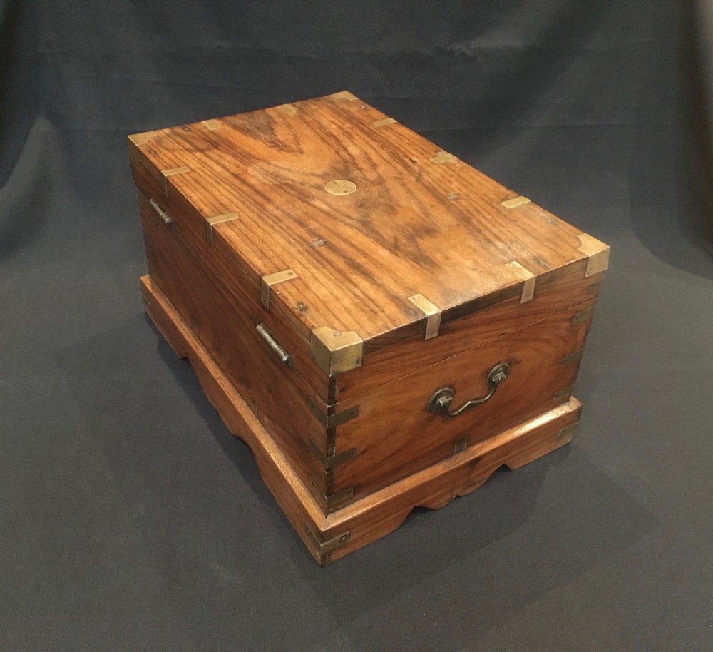 A rectangular warm brown oak desk box featuring brass bound corners, metal straps, a central brass oval cartouche, and a front keyhole escutcheon. View XI