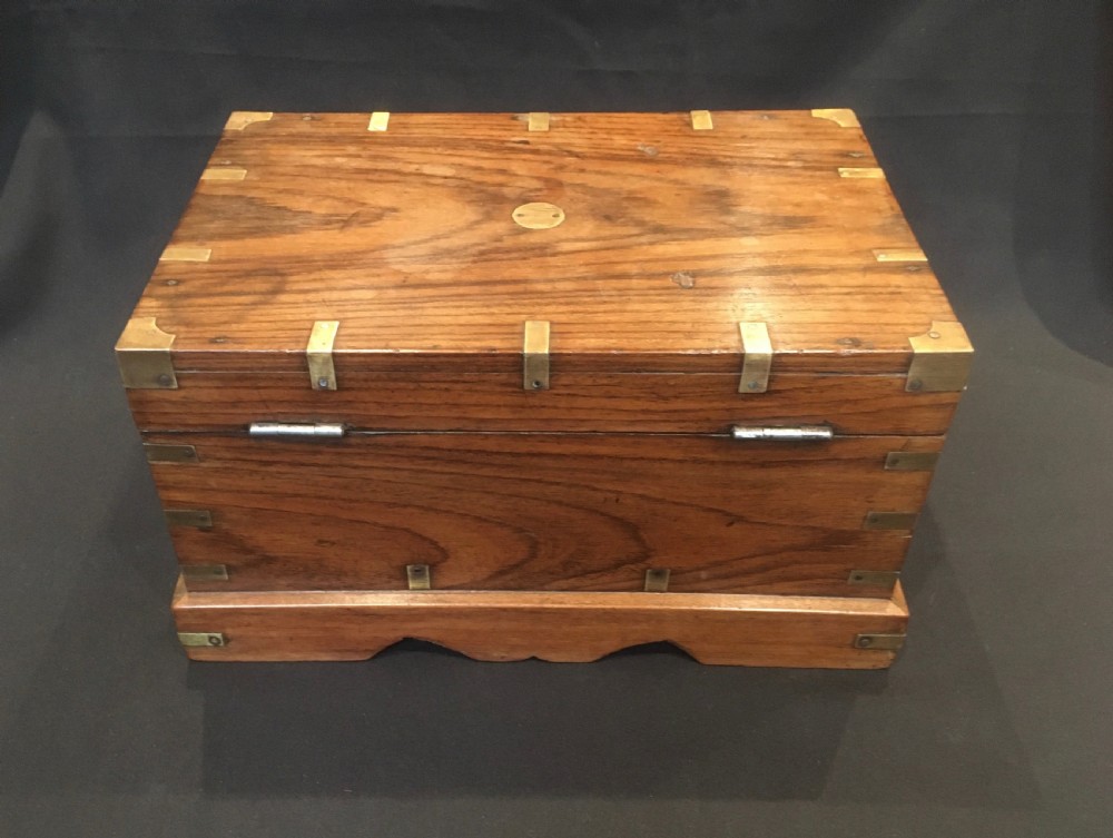 A rectangular warm brown oak desk box featuring brass bound corners, metal straps, a central brass oval cartouche, and a front keyhole escutcheon. View XII