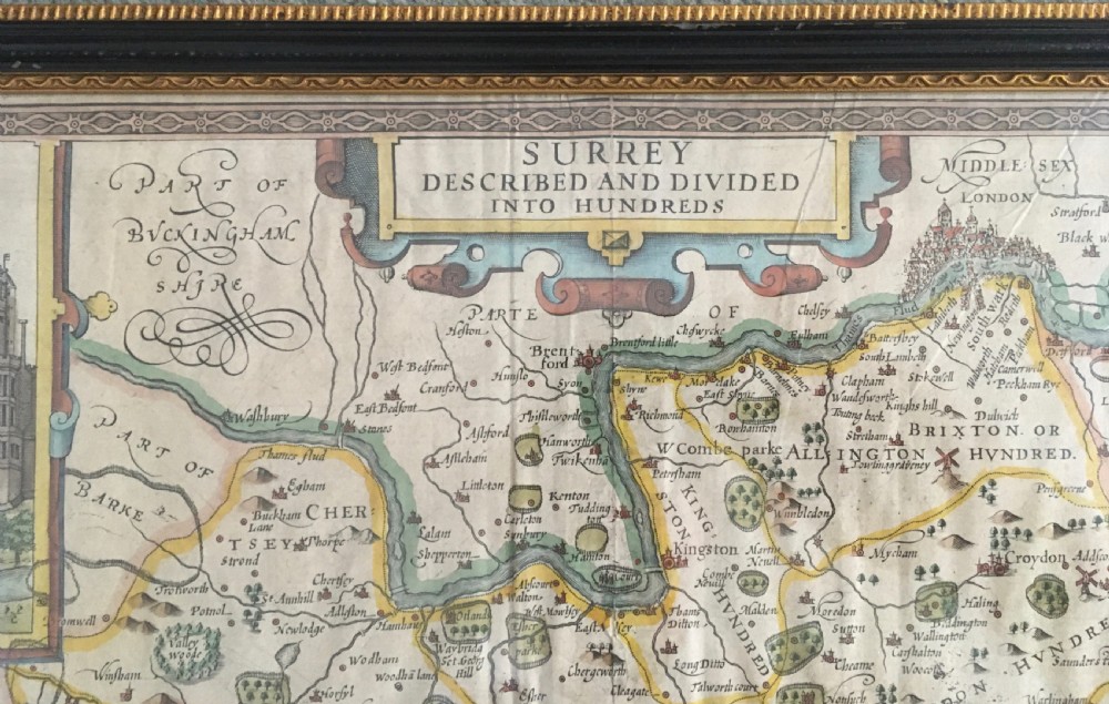 A framed historical map of Surrey by John Speed, displaying administrative divisions, coats of arms, and detailed corner insets of Richmond and Nonsuch palaces. View IV
