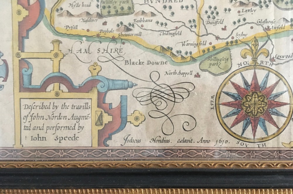 A framed historical map of Surrey by John Speed, displaying administrative divisions, coats of arms, and detailed corner insets of Richmond and Nonsuch palaces. View V