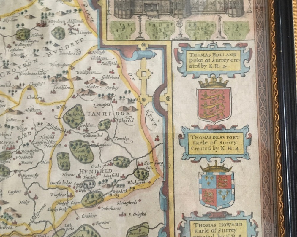 A framed historical map of Surrey by John Speed, displaying administrative divisions, coats of arms, and detailed corner insets of Richmond and Nonsuch palaces. View VII
