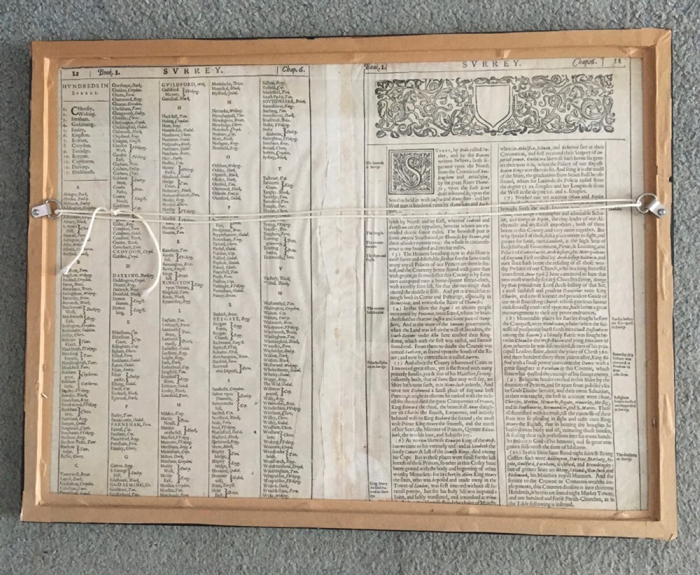 A framed historical map of Surrey by John Speed, displaying administrative divisions, coats of arms, and detailed corner insets of Richmond and Nonsuch palaces. View IX
