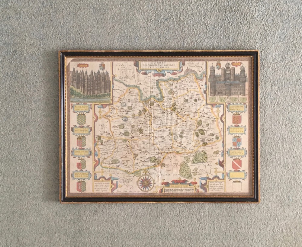 A framed historical map of Surrey by John Speed, displaying administrative divisions, coats of arms, and detailed corner insets of Richmond and Nonsuch palaces. View XII