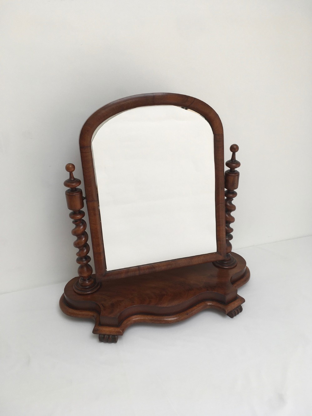 A Victorian mahogany dressing table mirror featuring an arched frame, spiral barley twist uprights, and a shaped plinth base with carved feet. View IV