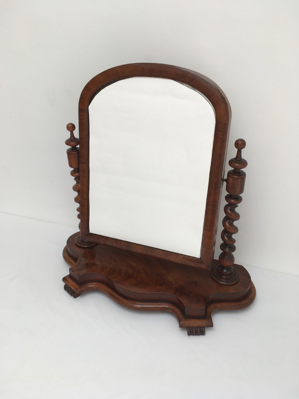 A Victorian mahogany dressing table mirror featuring an arched frame, spiral barley twist uprights, and a shaped plinth base with carved feet. View V