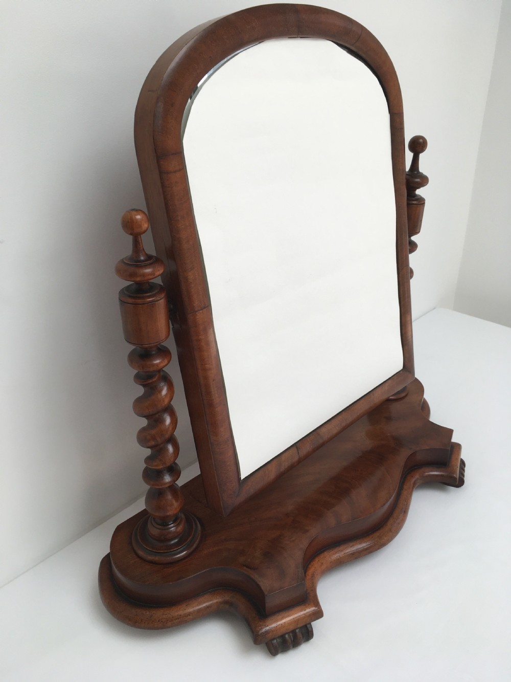 A Victorian mahogany dressing table mirror featuring an arched frame, spiral barley twist uprights, and a shaped plinth base with carved feet. View IX