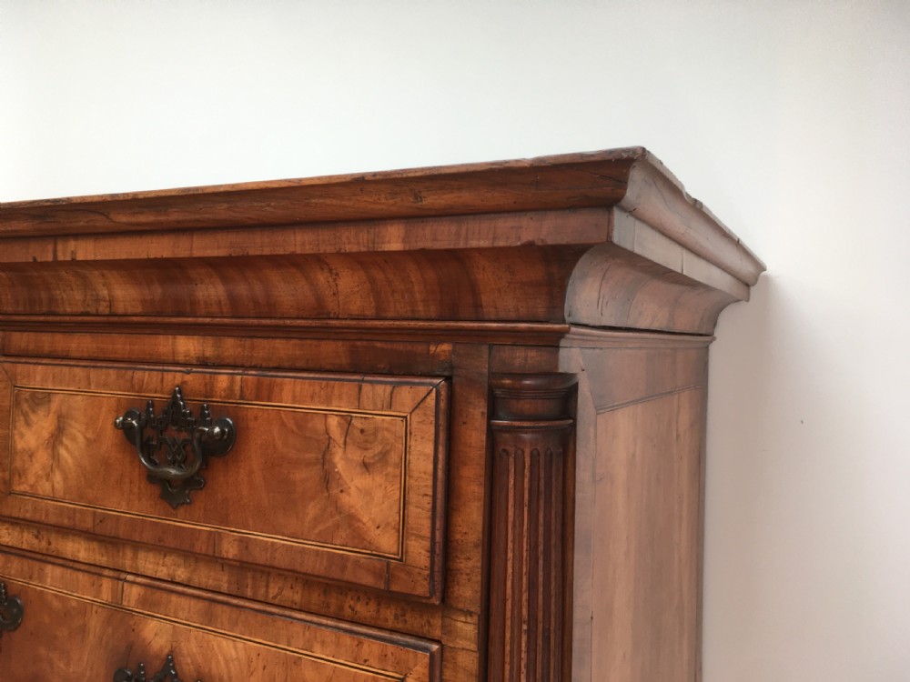 A George II walnut tallboy chest on chest featuring figured wood veneers, dark brass backplate handles, a moulded cornice, and bracket feet. View VII