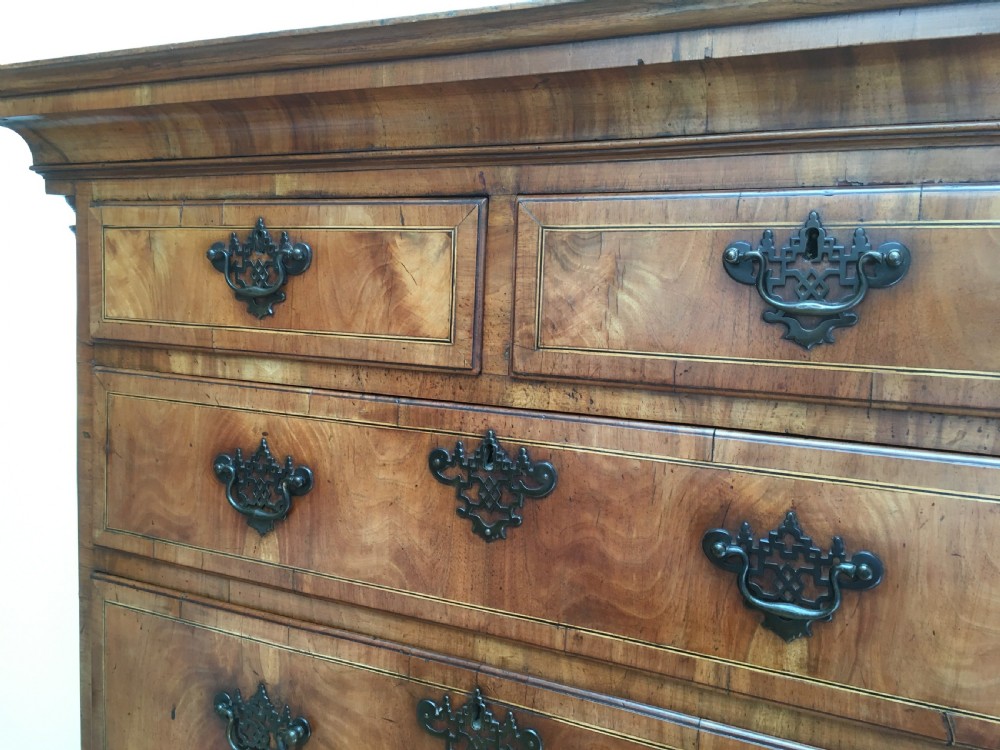 A George II walnut tallboy chest on chest featuring figured wood veneers, dark brass backplate handles, a moulded cornice, and bracket feet. View VIII