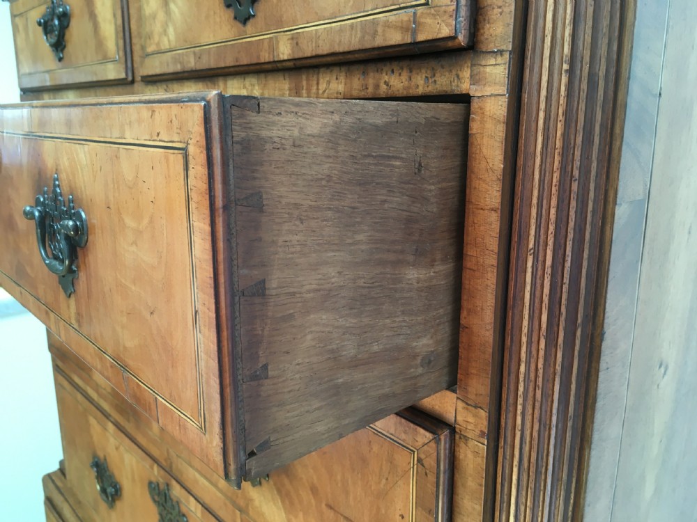A George II walnut tallboy chest on chest featuring figured wood veneers, dark brass backplate handles, a moulded cornice, and bracket feet. View IX
