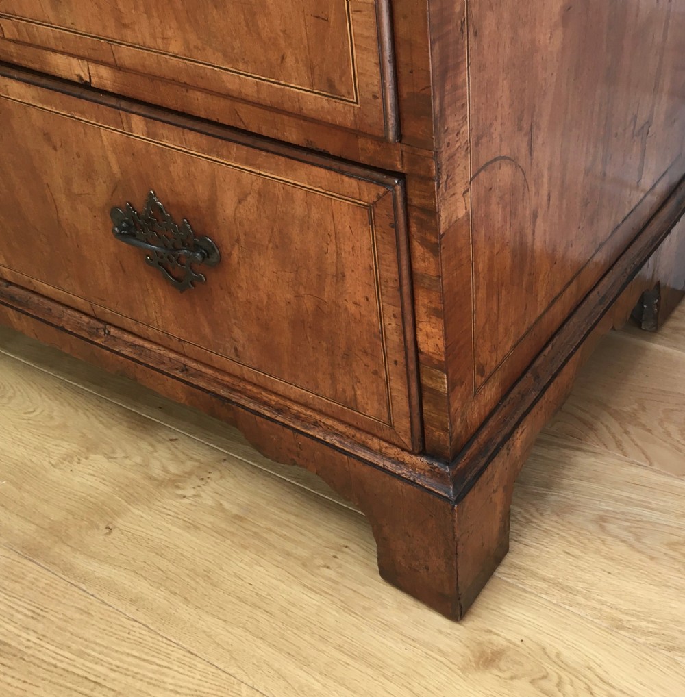 A George II walnut tallboy chest on chest featuring figured wood veneers, dark brass backplate handles, a moulded cornice, and bracket feet. View XI