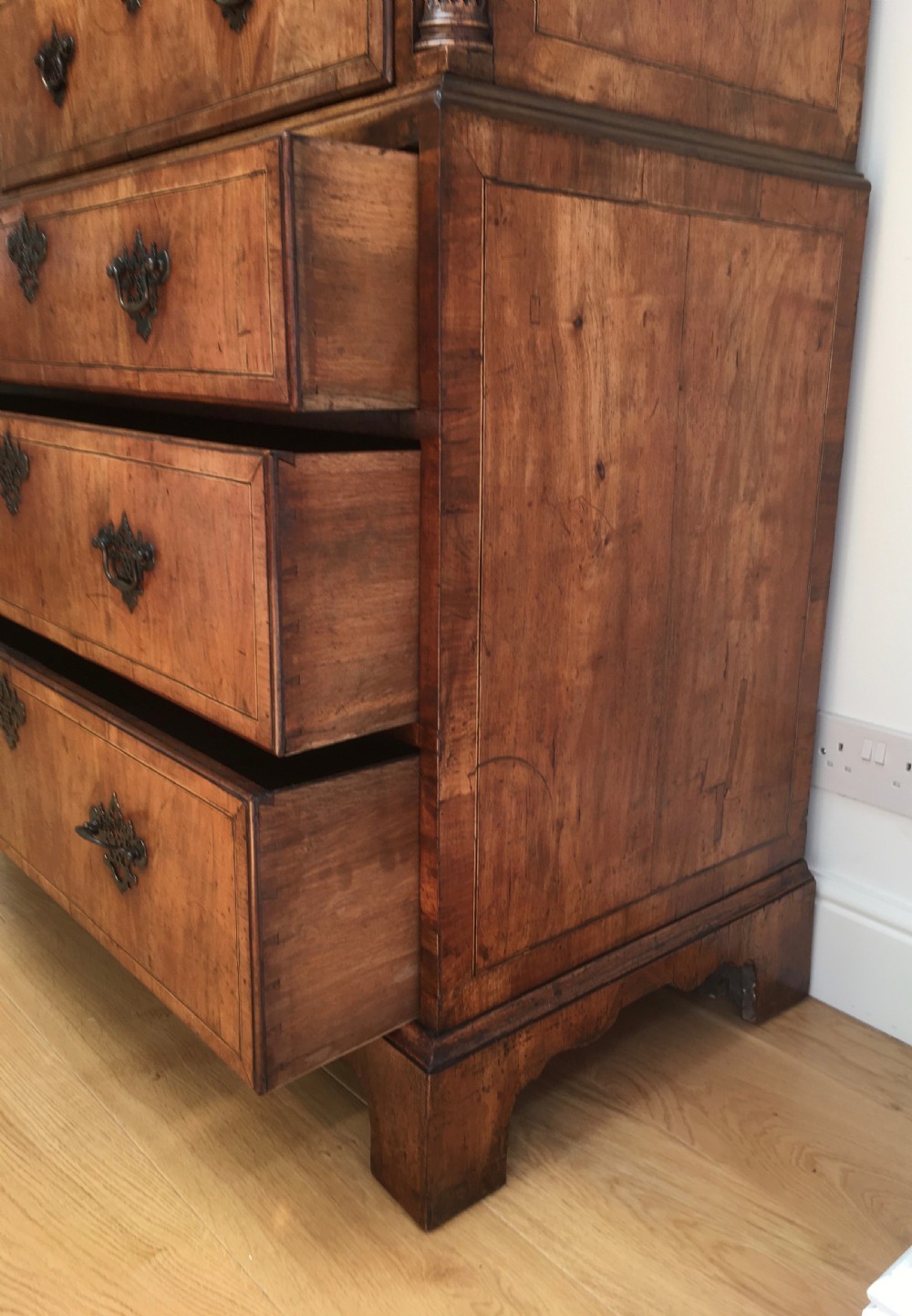 A George II walnut tallboy chest on chest featuring figured wood veneers, dark brass backplate handles, a moulded cornice, and bracket feet. View XIII