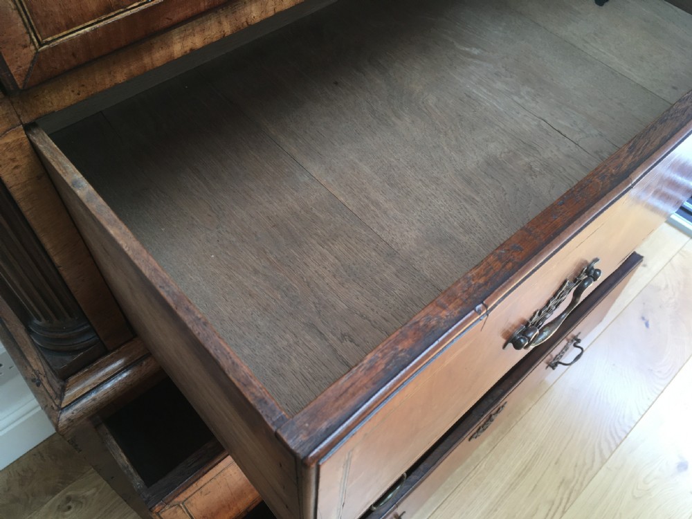 A George II walnut tallboy chest on chest featuring figured wood veneers, dark brass backplate handles, a moulded cornice, and bracket feet. View XIV