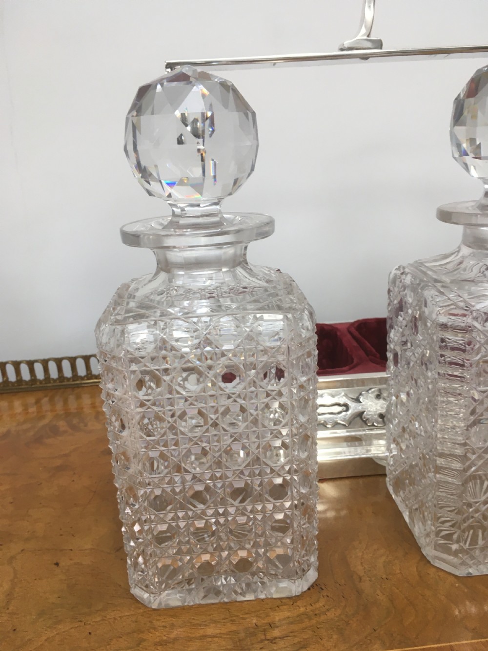 A silver-plated three-decanter tantalus featuring three cut-glass square decanters with facet-cut stoppers secured in a locking frame with a central handle. View XIII