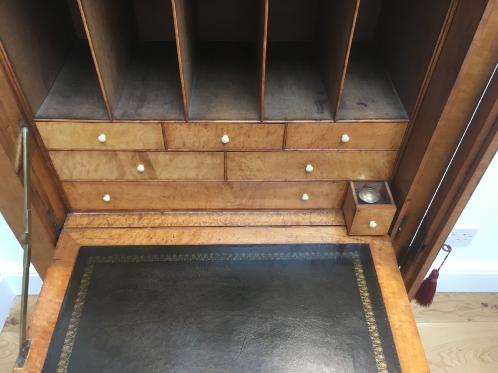 A tall Victorian birdseye maple secretaire Wellington chest featuring a hinged side locking bar, rosewood crossbanding, and a drop-down writing drawer revealing internal compartments. View IV