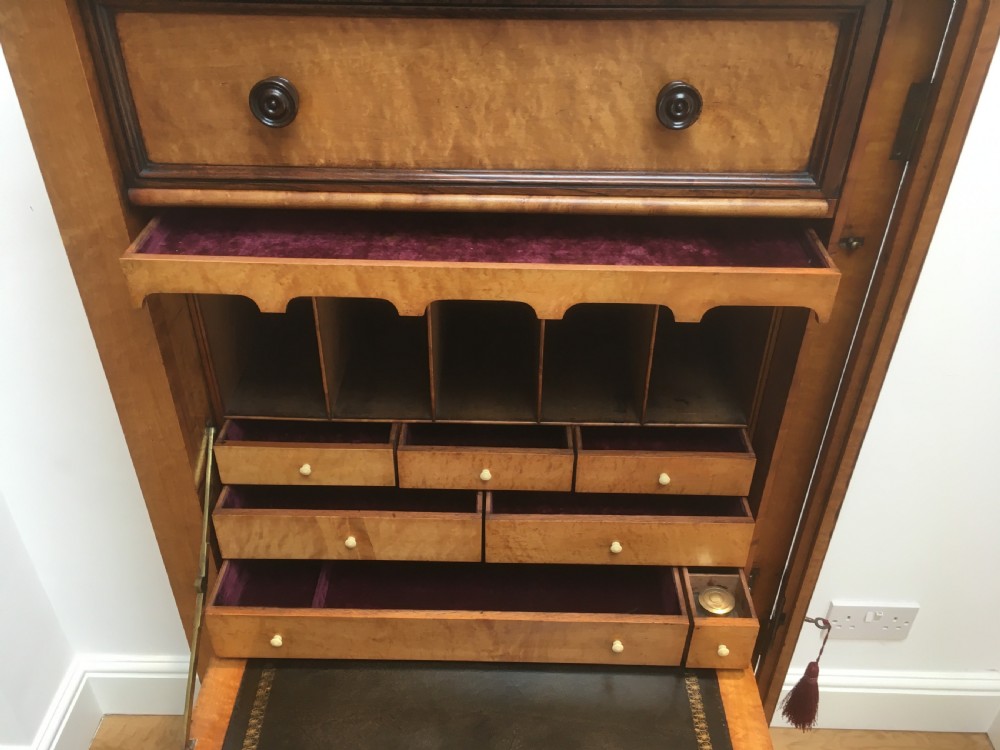 A tall Victorian birdseye maple secretaire Wellington chest featuring a hinged side locking bar, rosewood crossbanding, and a drop-down writing drawer revealing internal compartments. View V