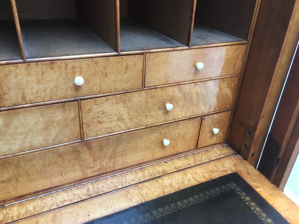 A tall Victorian birdseye maple secretaire Wellington chest featuring a hinged side locking bar, rosewood crossbanding, and a drop-down writing drawer revealing internal compartments. View VI