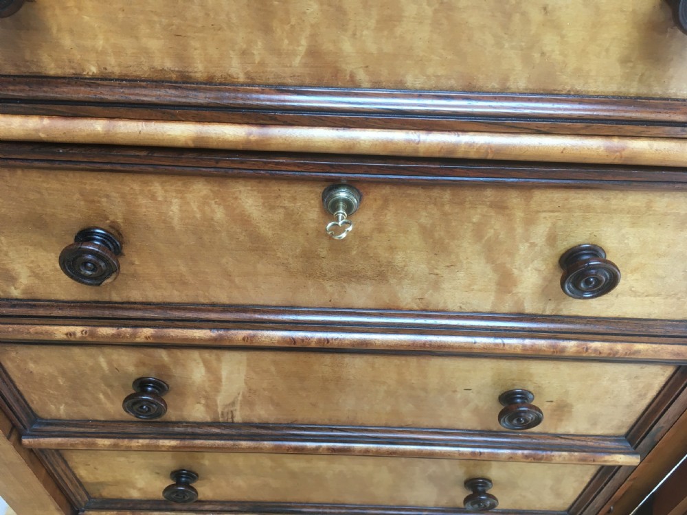A tall Victorian birdseye maple secretaire Wellington chest featuring a hinged side locking bar, rosewood crossbanding, and a drop-down writing drawer revealing internal compartments. View VIII