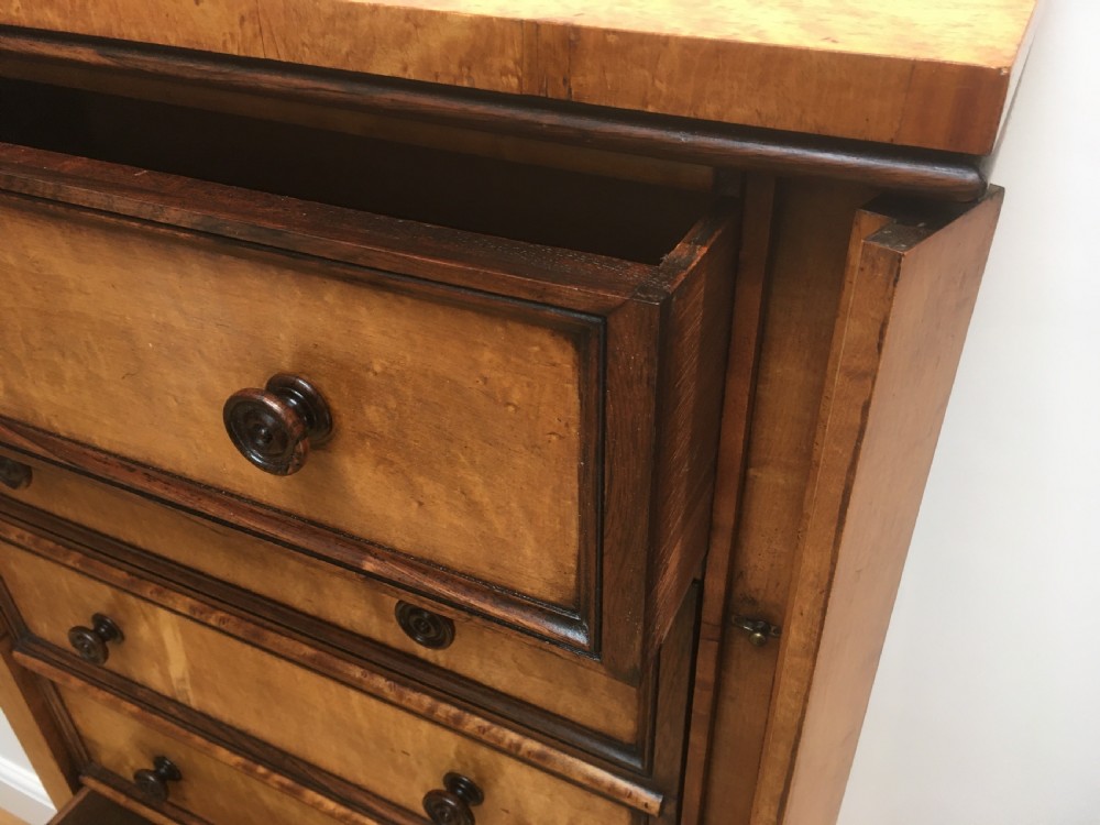 A tall Victorian birdseye maple secretaire Wellington chest featuring a hinged side locking bar, rosewood crossbanding, and a drop-down writing drawer revealing internal compartments. View X