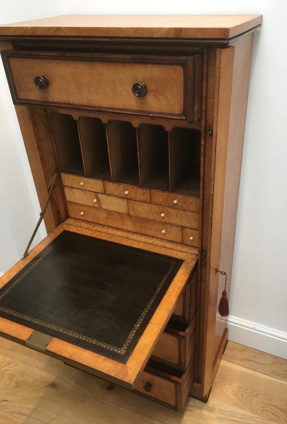A tall Victorian birdseye maple secretaire Wellington chest featuring a hinged side locking bar, rosewood crossbanding, and a drop-down writing drawer revealing internal compartments. View XI