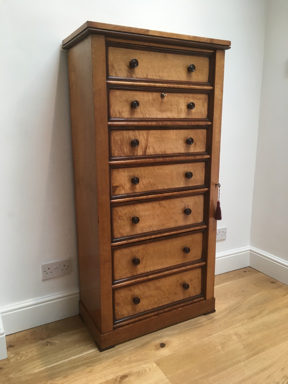 A tall Victorian birdseye maple secretaire Wellington chest featuring a hinged side locking bar, rosewood crossbanding, and a drop-down writing drawer revealing internal compartments. View XV