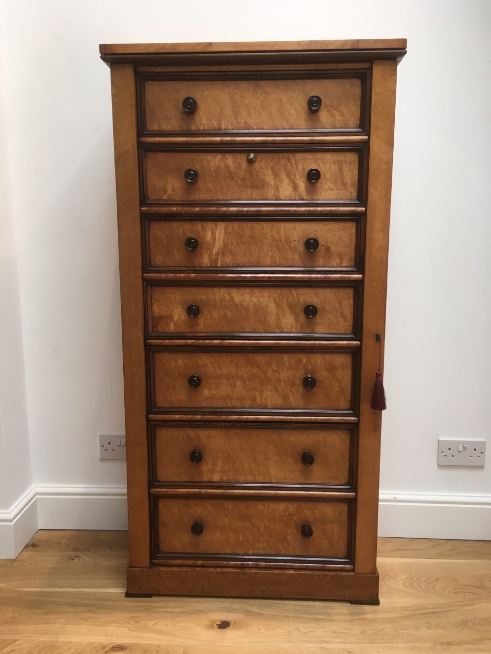 A tall Victorian birdseye maple secretaire Wellington chest featuring a hinged side locking bar, rosewood crossbanding, and a drop-down writing drawer revealing internal compartments. View XVI